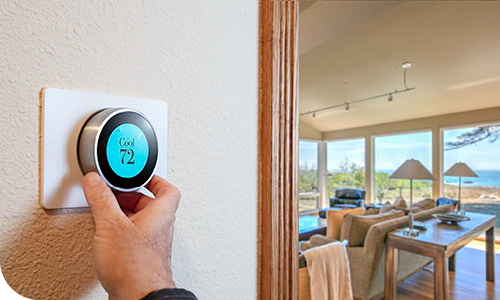 "a hand adjusting a smart thermostat"